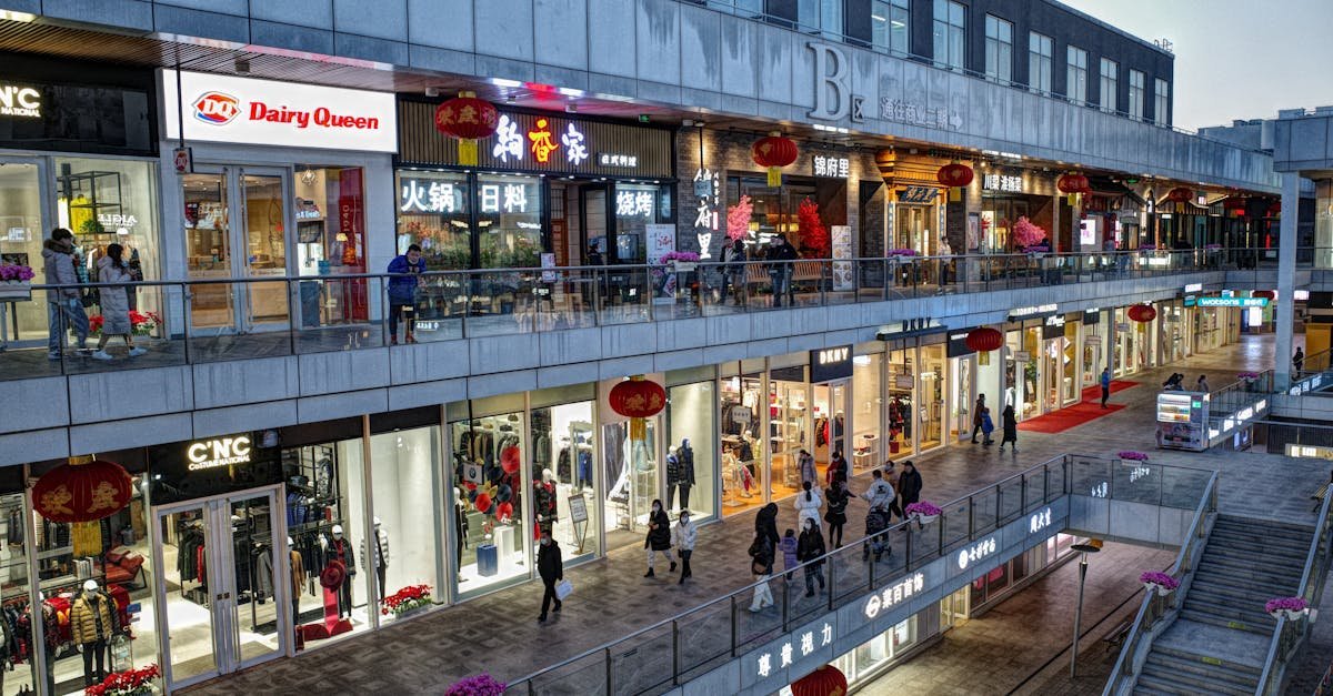 Bustling evening at a modern shopping mall with various shops and pedestrians.